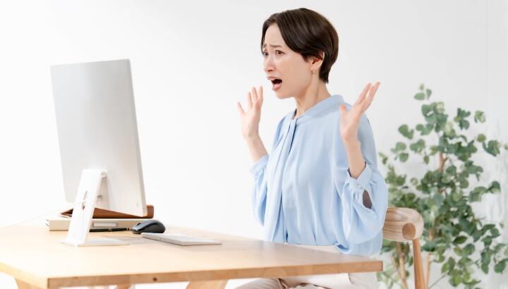 パソコンの画面を見て驚いている女性
